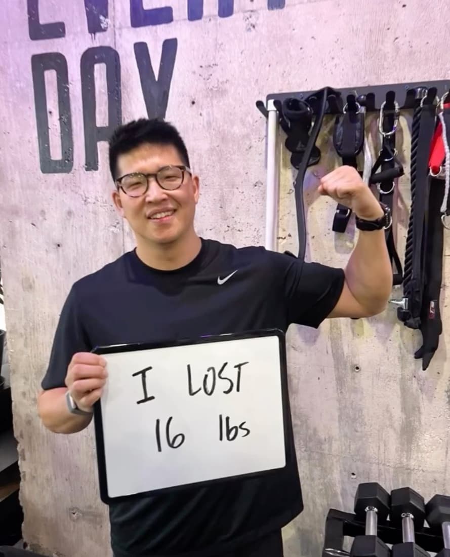 Leaner Fitness member holding a sign reading I lost 16 lbs